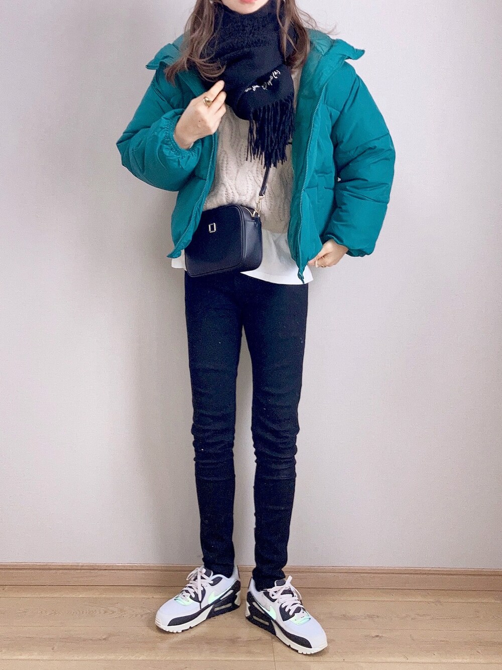グリーン系のダウンジャケット/コート、ホワイト系のニット/セーター、ブラック系のショルダーバッグを着用したレディースの冬コーディネートの2枚目の写真