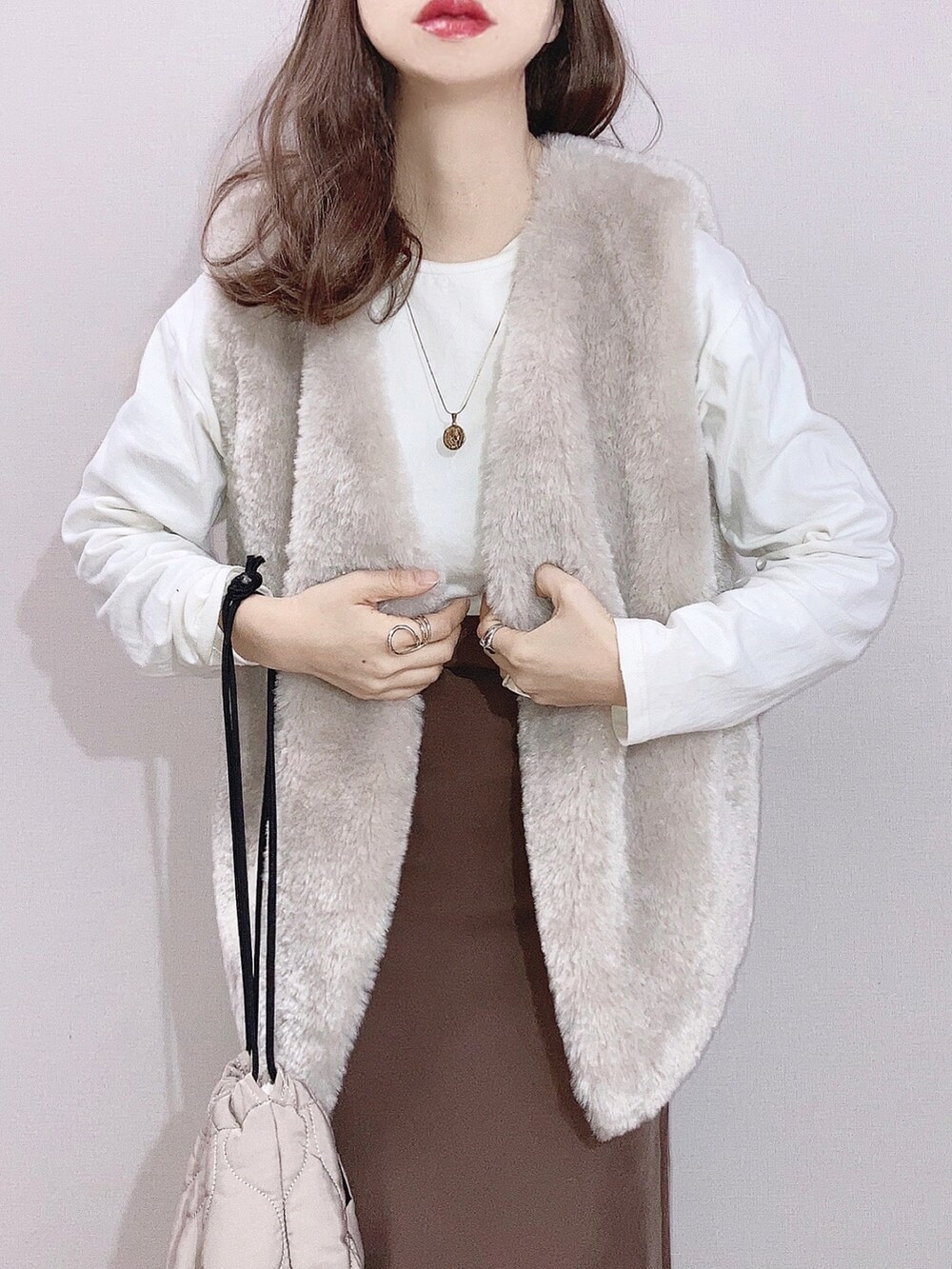 グレー系のベスト、ホワイト系のTシャツ/カットソー、ブラウン系のスカートを着用したレディースの冬コーディネートの2枚目の写真