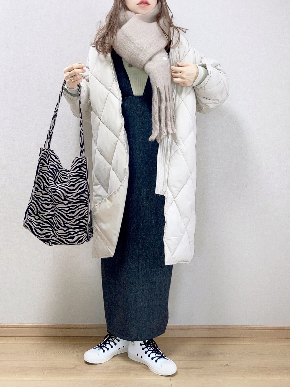 ホワイト系のダウンジャケット/コート、ブラック系のジャンパースカート、ホワイト系のスニーカーを着用したレディースの冬コーディネートの2枚目の写真