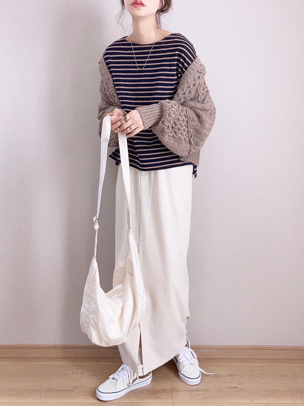 ブラック系のTシャツ/カットソー、ブラウン系のカーディガン/ボレロ、ホワイト系のスカートを着用したレディースの秋コーディネートの2枚目の写真