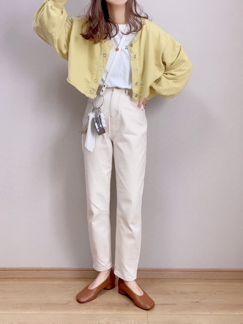 イエロー系のスウェット、ホワイト系のTシャツ/カットソー、ベージュ系のデニムパンツを着用したレディースの冬コーディネートの2枚目の写真