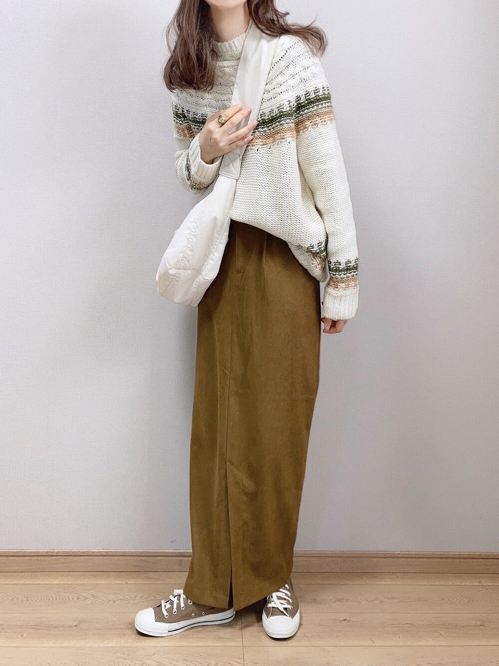 グリーン系のニット/セーター、ホワイト系のショルダーバッグ、ブラウン系のスカートを着用したレディースの冬コーディネートの2枚目の写真