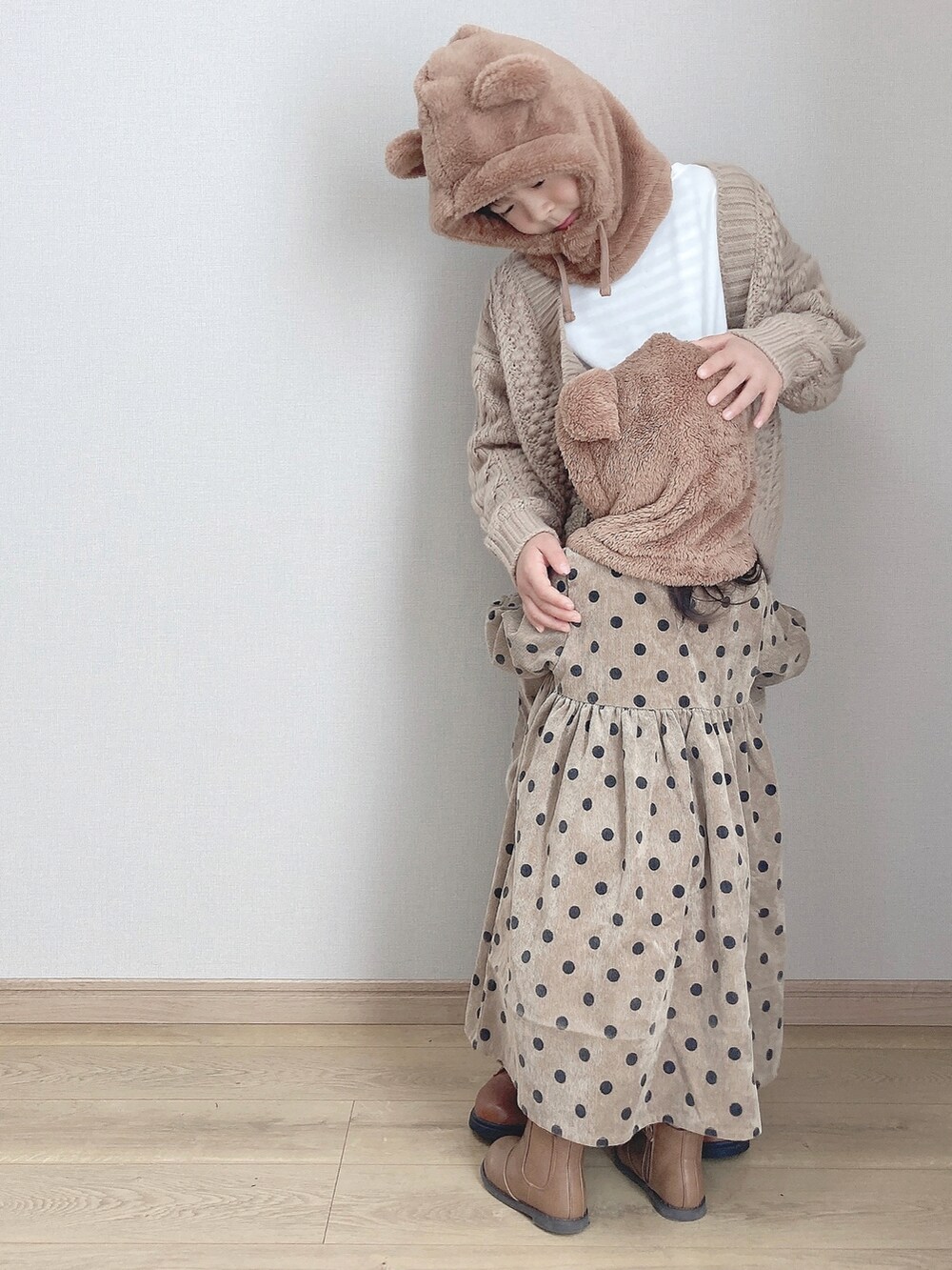 ベージュ系のワンピース、ブラウン系のブーツ、ベージュ系のカーディガン/ボレロを着用したキッズの秋コーディネートの2枚目の写真