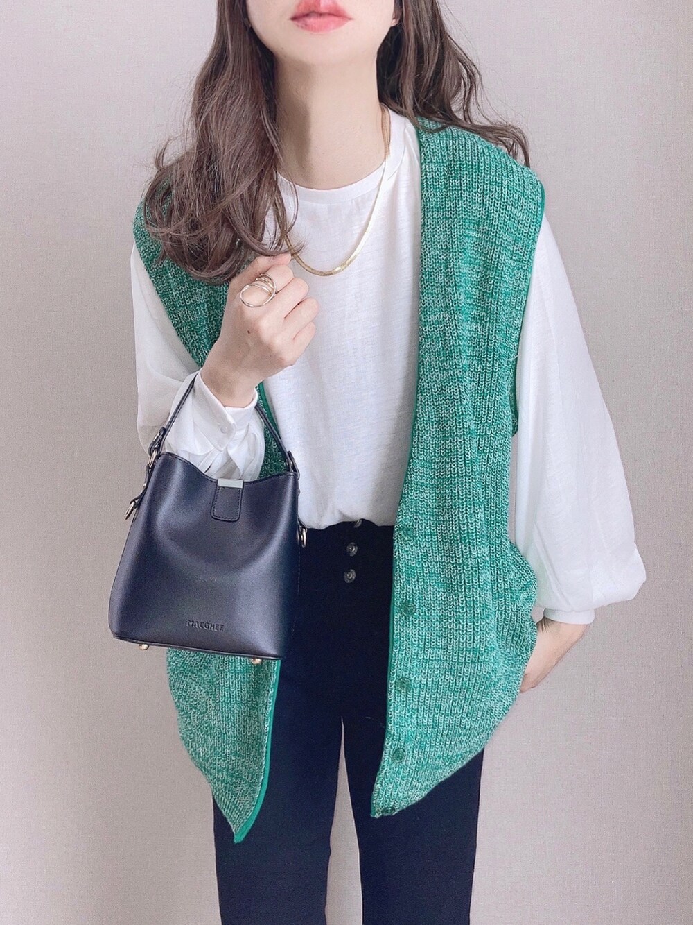 グリーン系のベスト、ブラック系のデニムパンツ、ブラック系のショルダーバッグを着用したレディースの冬コーディネートの2枚目の写真