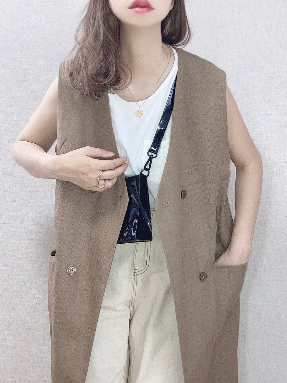 ブラウン系のベスト、ホワイト系のTシャツ/カットソー、ベージュ系のデニムパンツを着用したレディースの春コーディネートの2枚目の写真