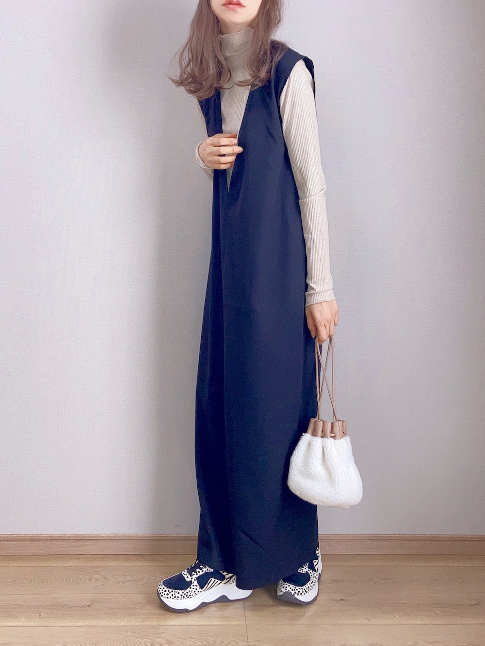 ベージュ系のTシャツ/カットソー、ブラック系のワンピース、ベージュ系のハンドバッグを着用したレディースの秋コーディネートの2枚目の写真