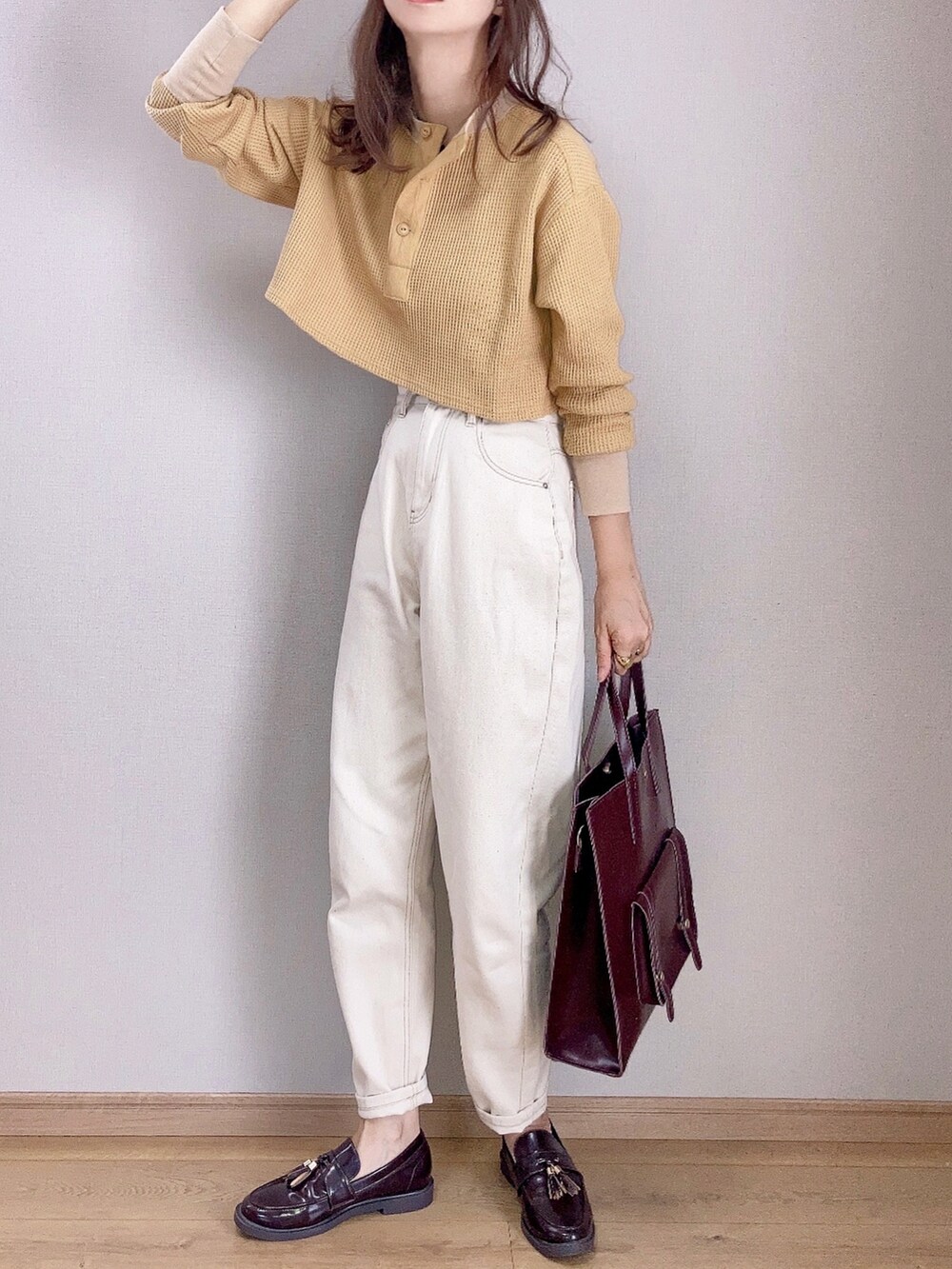 イエロー系のTシャツ/カットソー、ベージュ系のデニムパンツ、ブラウン系のハンドバッグを着用したレディースの秋コーディネートの2枚目の写真