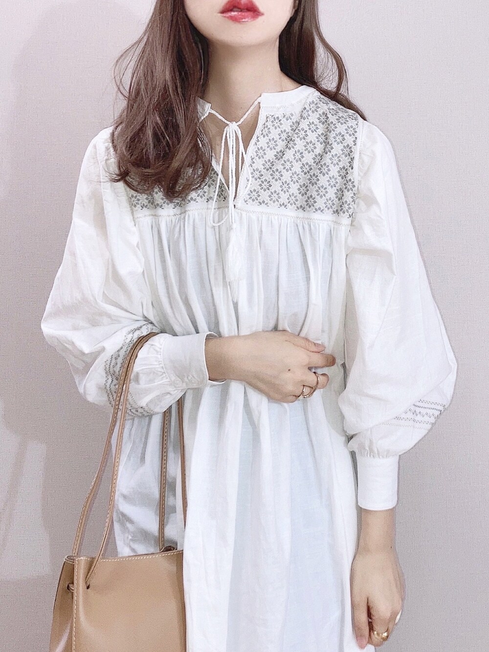 ホワイト系のワンピース、ブルー系のデニムパンツ、ベージュ系のショルダーバッグを着用したレディースの春コーディネートの2枚目の写真