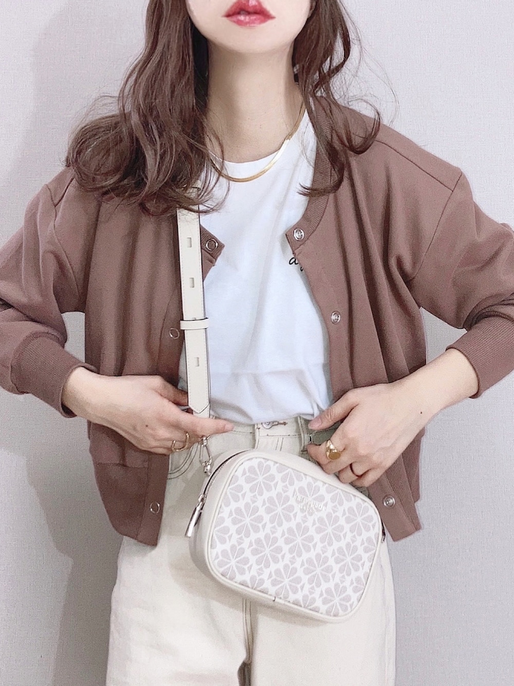 ホワイト系のショルダーバッグ、ブラウン系のカーディガン/ボレロ、ホワイト系のTシャツ/カットソーを着用したレディースの春コーディネートの2枚目の写真