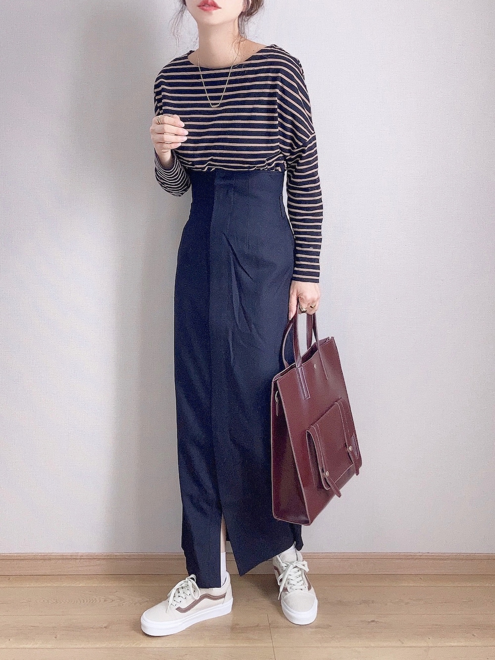 ブラック系のTシャツ/カットソー、ブラック系のスカート、ブラウン系のハンドバッグを着用したレディースの秋コーディネートの2枚目の写真