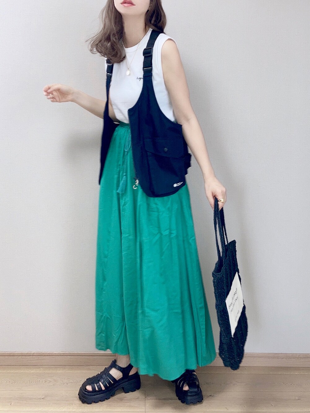 グリーン系のスカート、ホワイト系のTシャツ/カットソー、ブルー系のベストを着用したレディースの春コーディネートの2枚目の写真