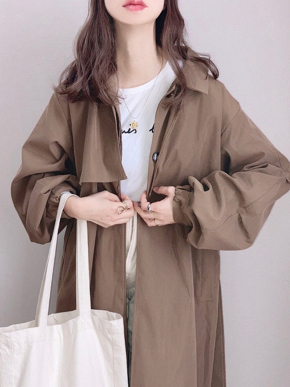 ブラウン系のトレンチコート、ホワイト系のTシャツ/カットソー、ホワイト系のデニムパンツを着用したレディースの春コーディネートの2枚目の写真