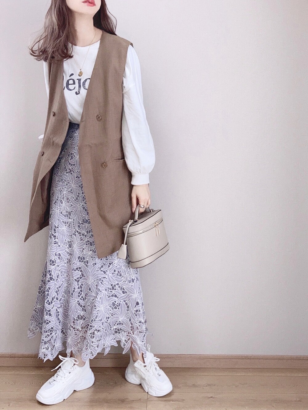 ブルー系のスカート、ホワイト系のスニーカー、ブラウン系のベストを着用したレディースの春コーディネートの3枚目の写真