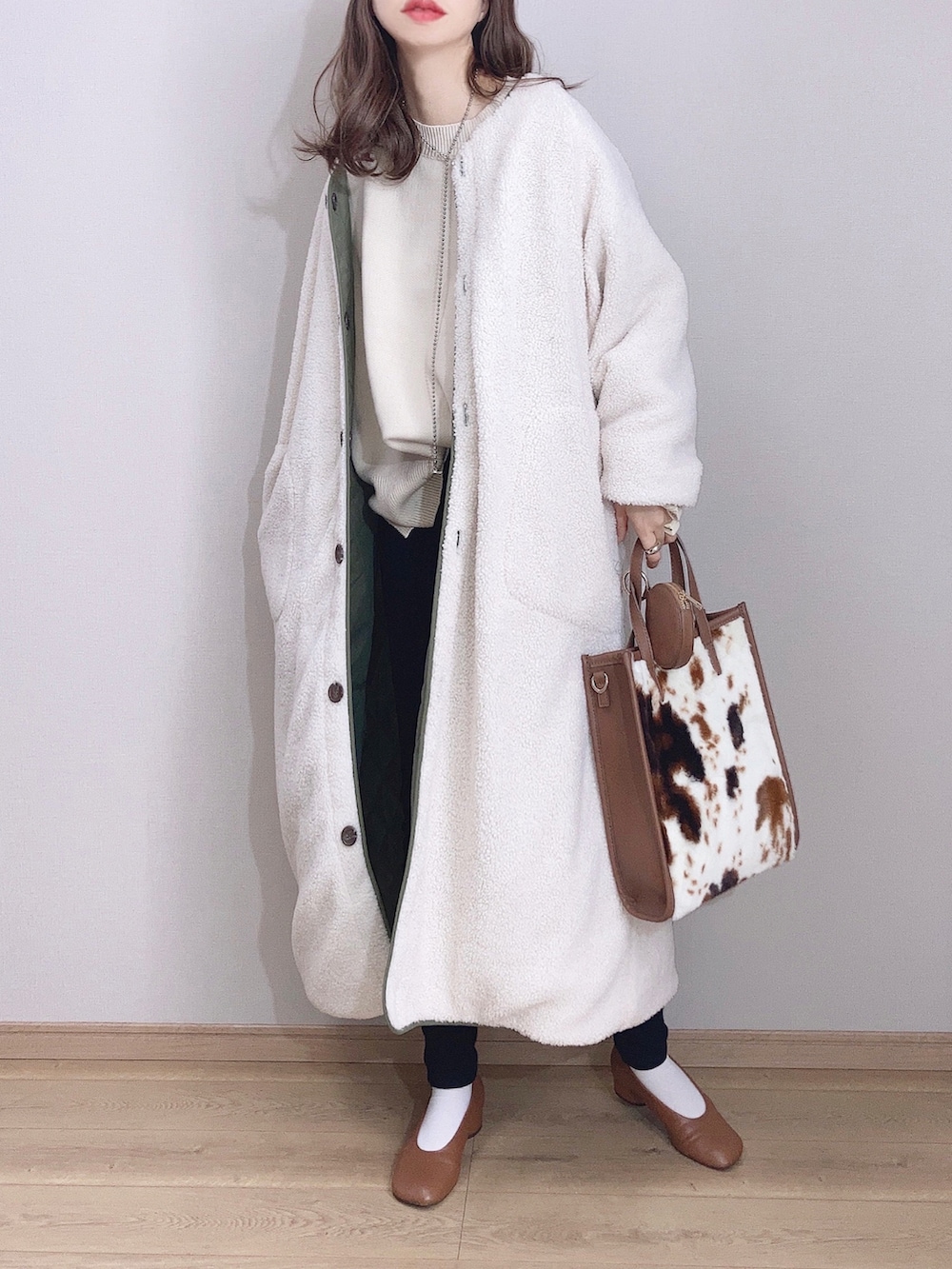 グリーン系のダウンジャケット/コート、ホワイト系のニット/セーター、ブラック系のバックパック/リュックを着用したレディースの冬コーディネートの3枚目の写真