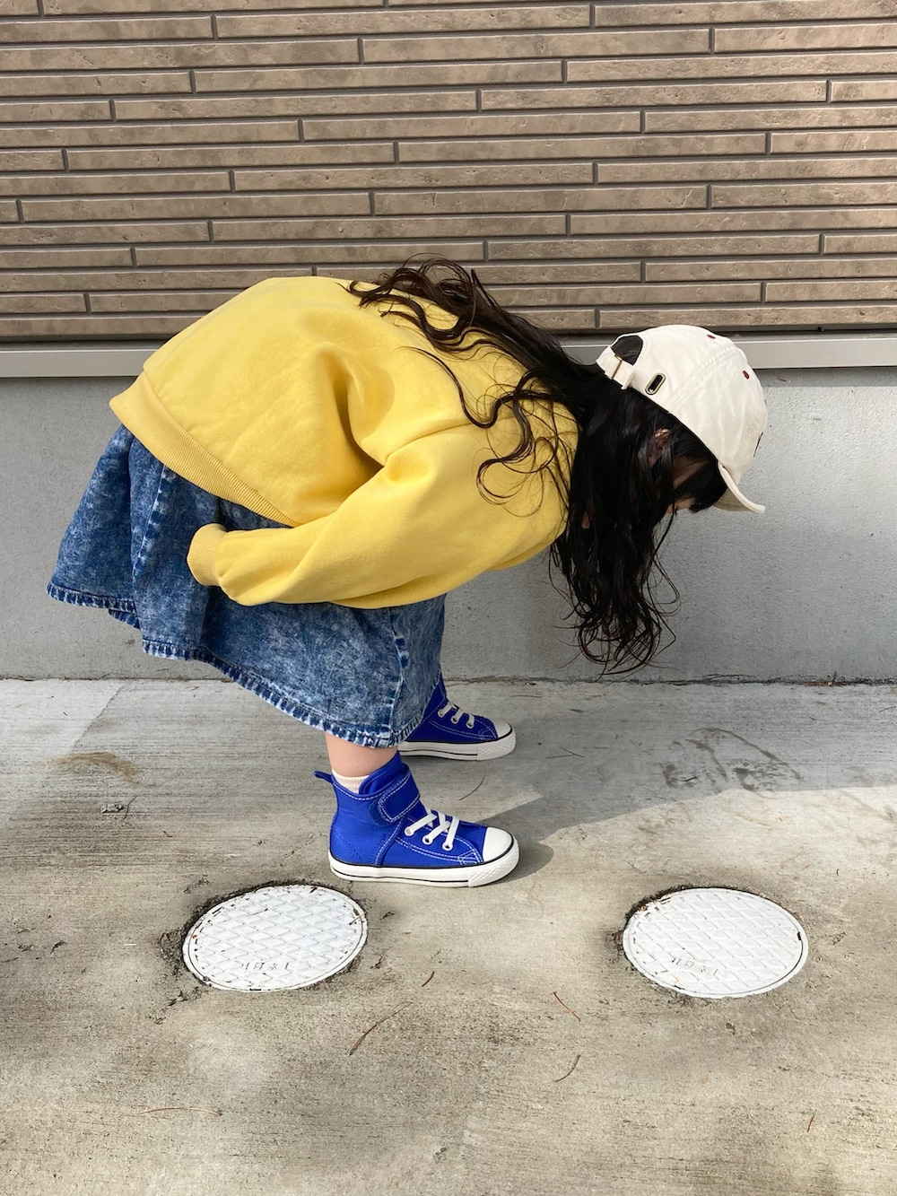 イエロー系のスウェット、ブルー系のデニムスカート、ブルー系のスニーカーを着用したキッズの春コーディネートの2枚目の写真