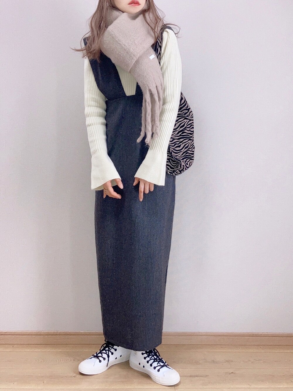 ホワイト系のニット/セーター、ブラック系のジャンパースカート、グレー系のショルダーバッグを着用したレディースの冬コーディネートの2枚目の写真