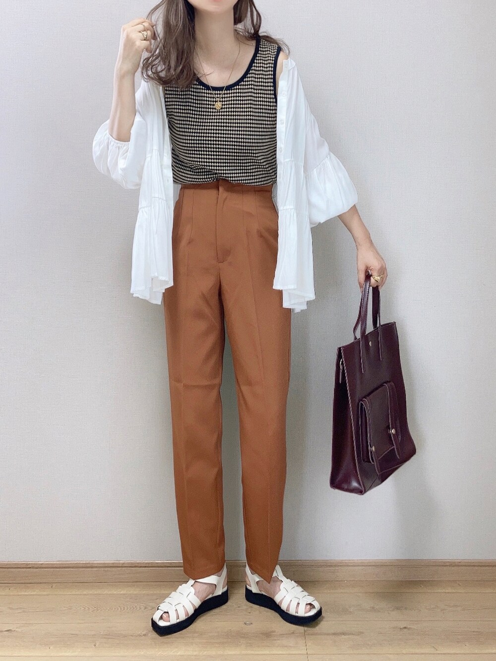 ブラック系のタンクトップ、ブラウン系のハンドバッグ、ホワイト系のサンダルを着用したレディースの夏コーディネートの2枚目の写真