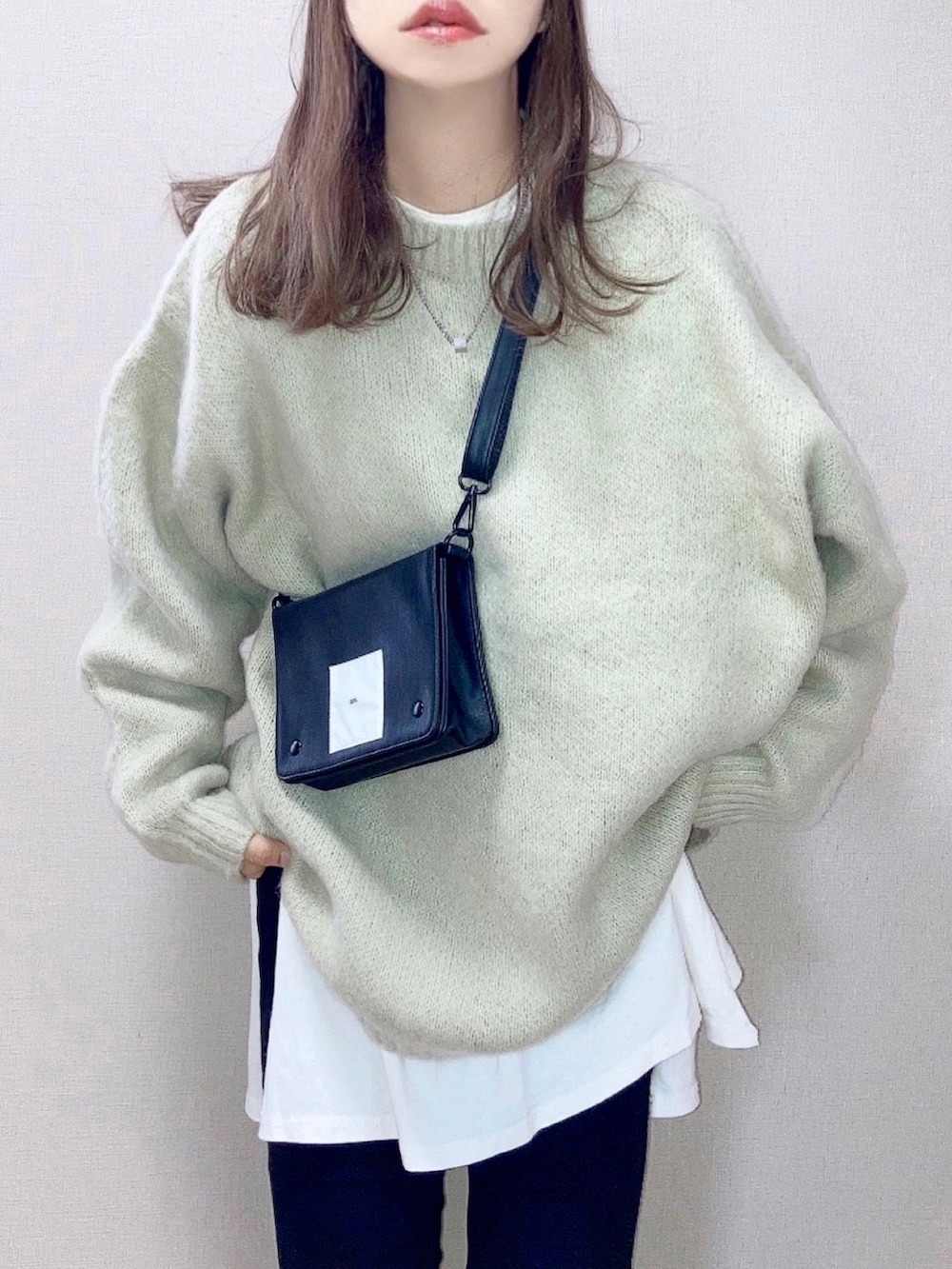 ベージュ系のニット/セーター、ホワイト系のTシャツ/カットソー、ブラック系のショルダーバッグを着用したレディースの秋コーディネートの2枚目の写真