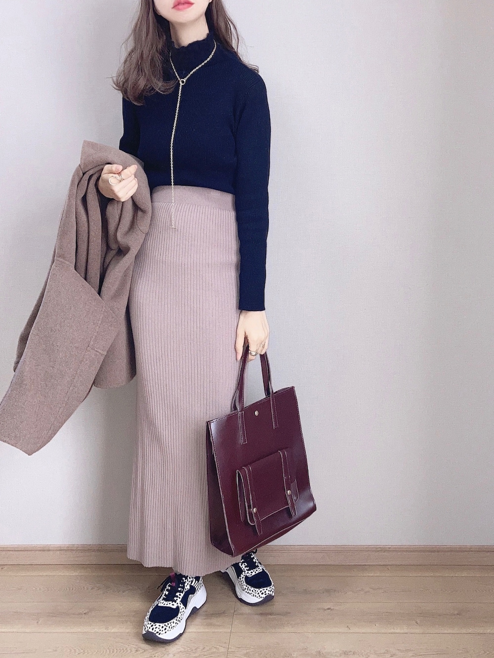 ブラウン系のピーコート、ブラック系のニット/セーター、ベージュ系のスカートを着用したレディースの冬コーディネートの2枚目の写真