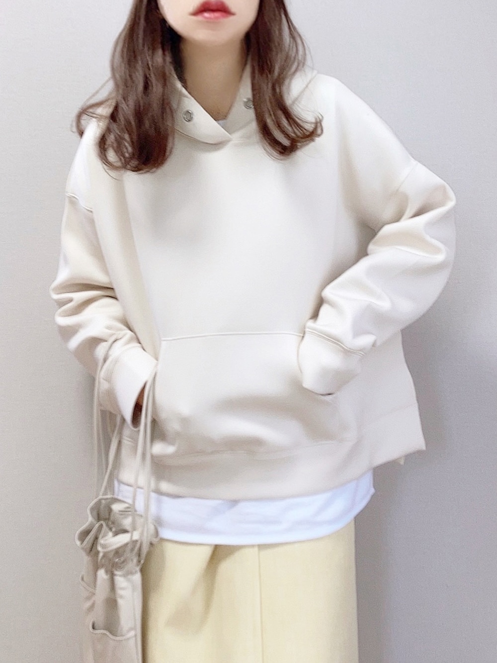 ベージュ系のパーカー、イエロー系のスカート、ベージュ系のショルダーバッグを着用したレディースの冬コーディネートの3枚目の写真