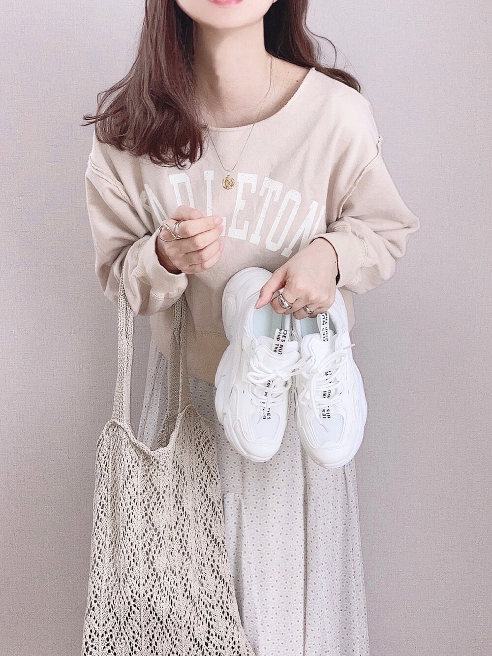 グリーン系のスカート、ベージュ系のスウェット、ホワイト系のスニーカーを着用したレディースの春コーディネートの3枚目の写真