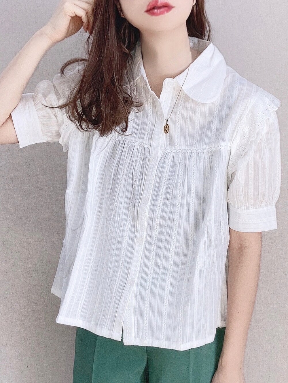 ホワイト系のシャツ/ブラウス、グリーン系のスラックス、ベージュ系のハンドバッグを着用したレディースの春コーディネートの2枚目の写真