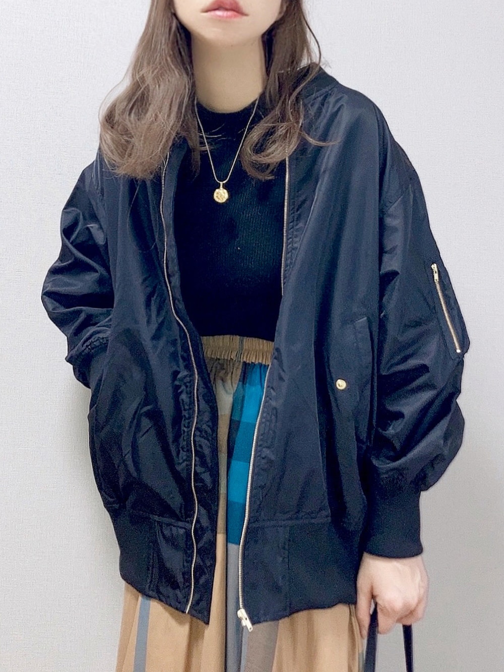 ブラック系のブルゾン、ブラック系のニット/セーター、イエロー系のスカートを着用したレディースの冬コーディネートの3枚目の写真