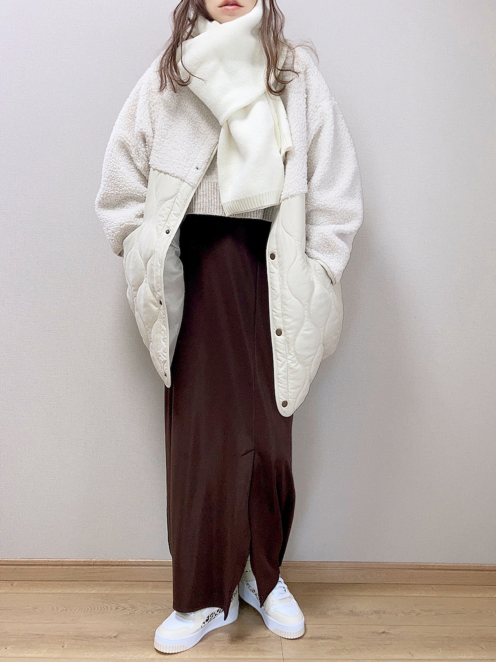 ホワイト系のブルゾン、ベージュ系のニット/セーター、ブラウン系のスカートを着用したレディースの秋コーディネートの2枚目の写真