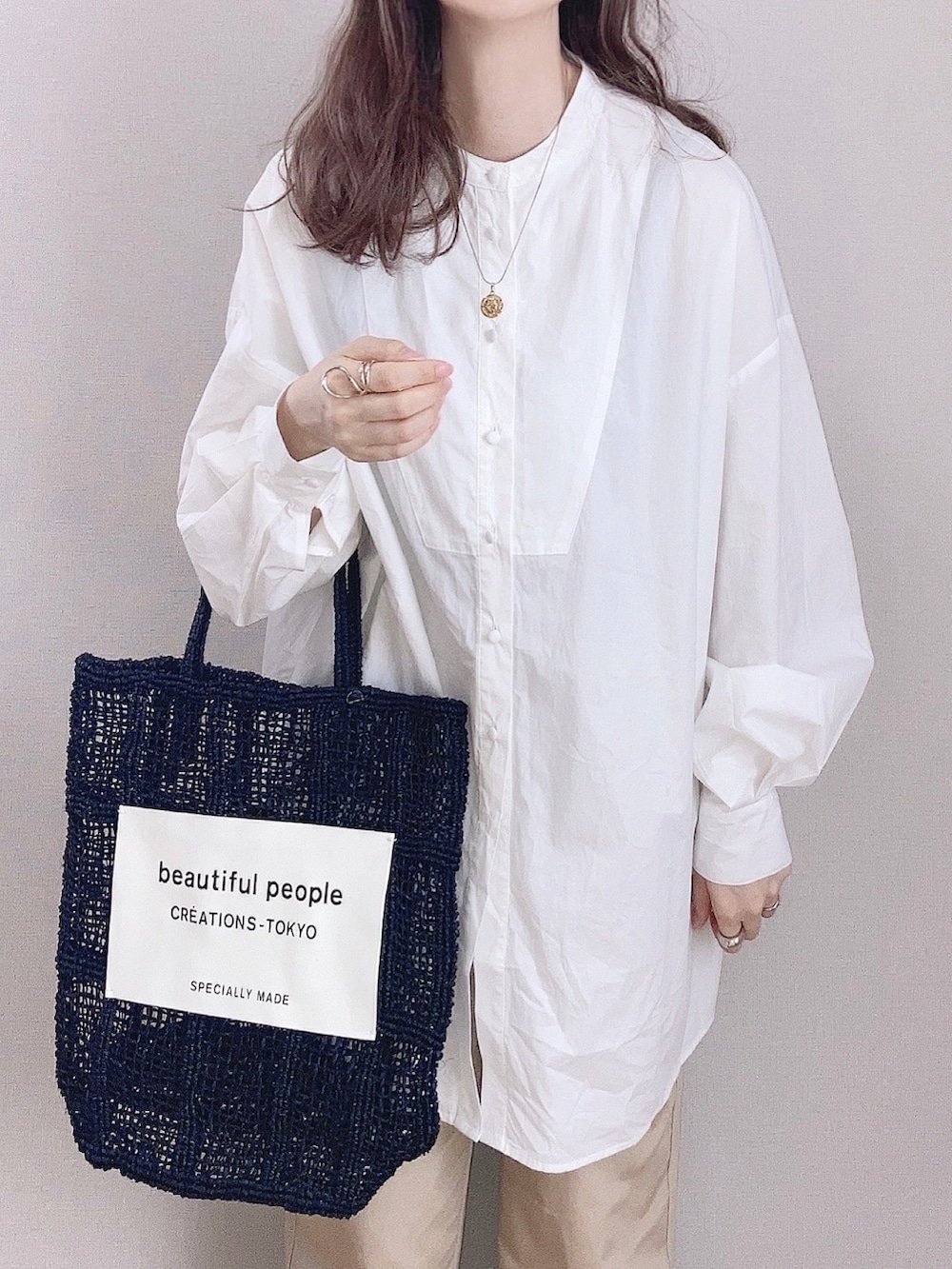 ベージュ系のチノパンツ、ホワイト系のシャツ/ブラウス、ブラック系のトートバッグを着用したレディースの春コーディネートの3枚目の写真