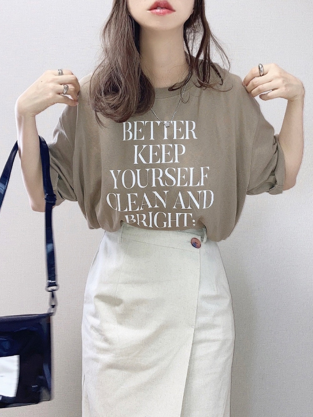 ベージュ系のTシャツ/カットソー、ベージュ系のスカート、ブラック系のショルダーバッグを着用したレディースの夏コーディネートの2枚目の写真