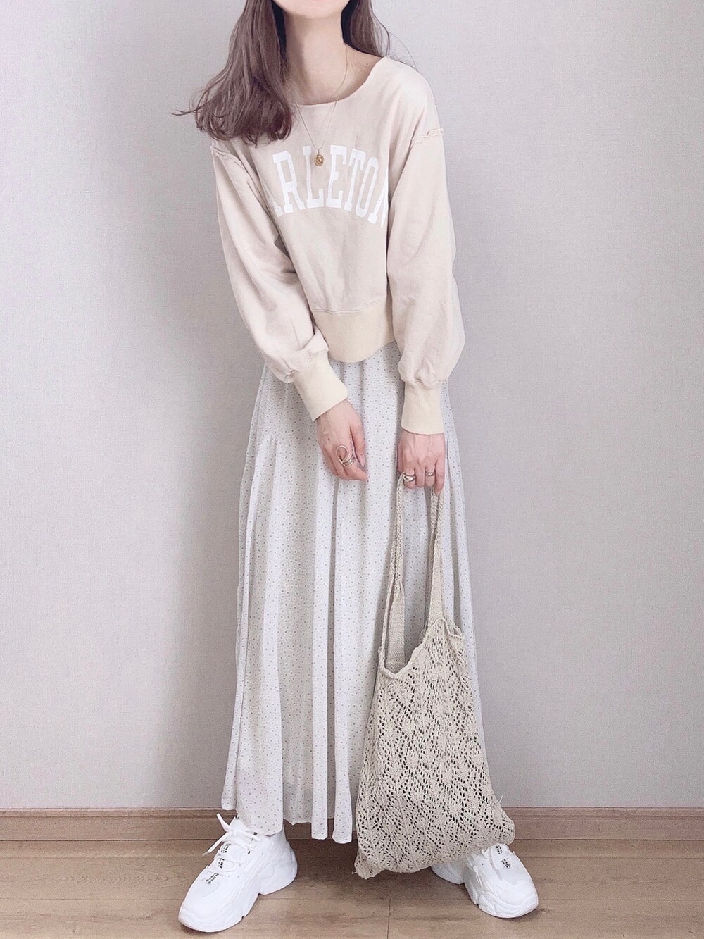 グリーン系のスカート、ベージュ系のスウェット、ホワイト系のスニーカーを着用したレディースの春コーディネートの2枚目の写真