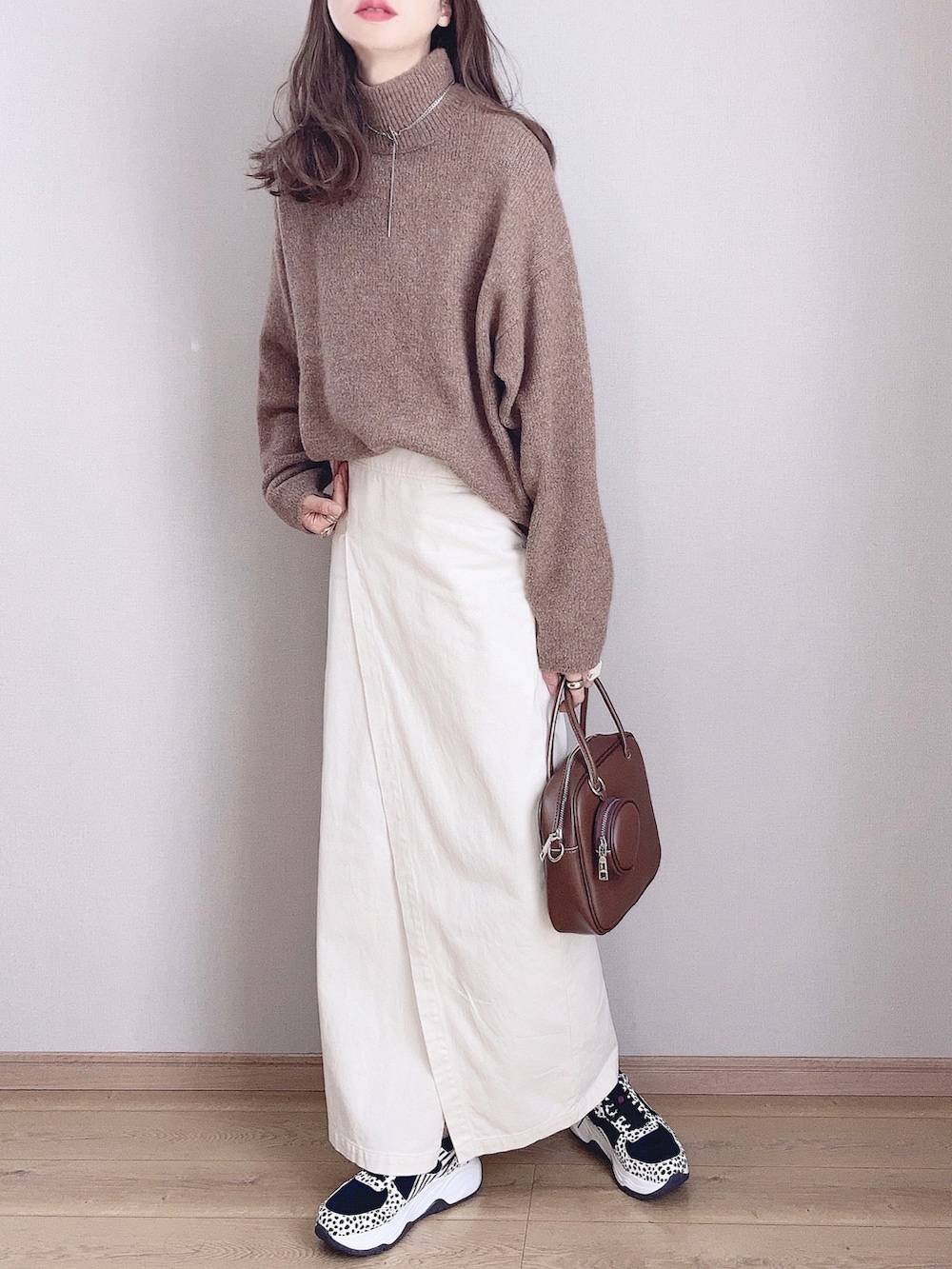 ブラウン系のピーコート、ブラウン系のニット/セーター、ホワイト系のスカートを着用したレディースの秋コーディネートの3枚目の写真