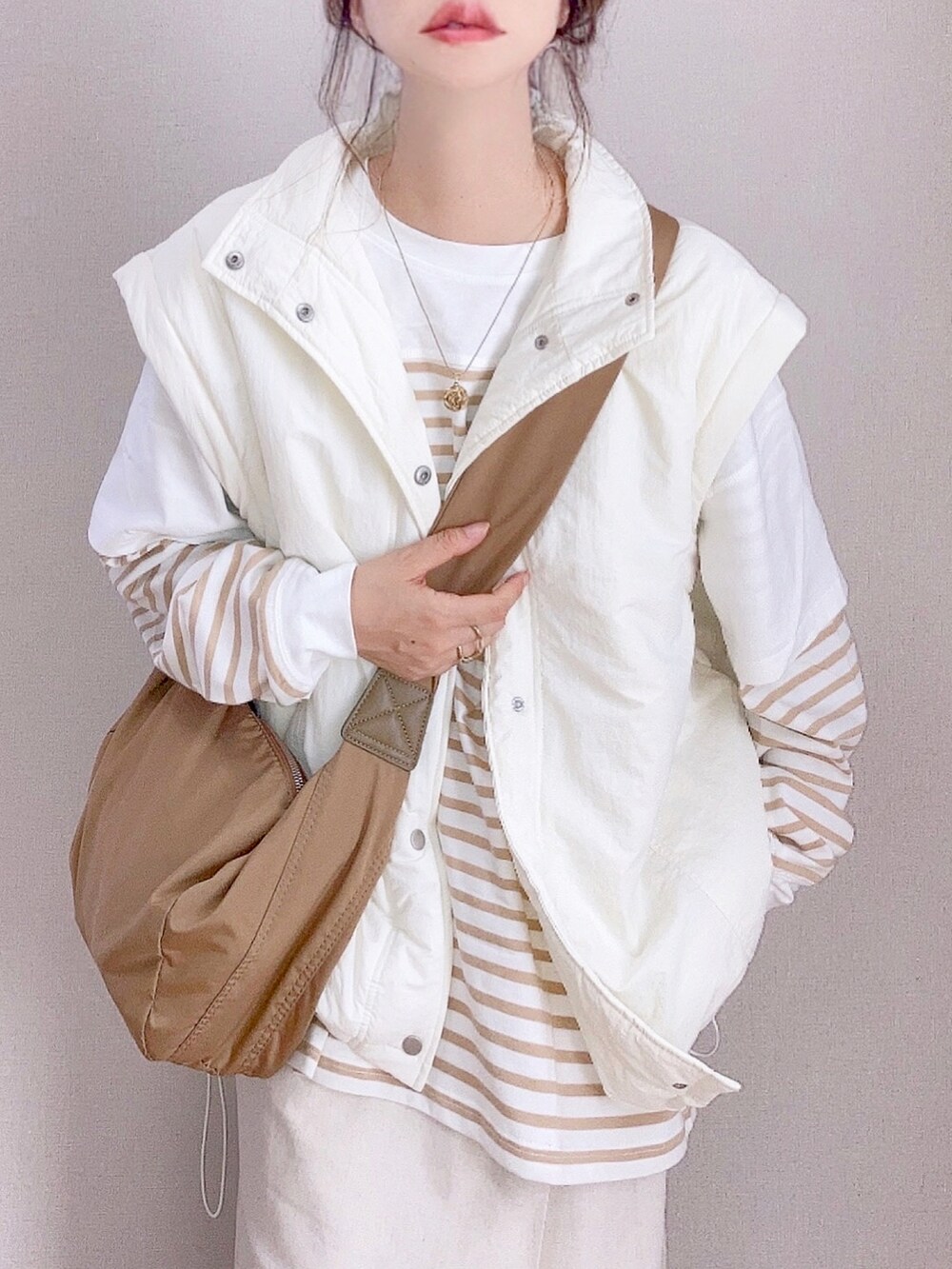 ホワイト系のダウンジャケット/コート、ベージュ系のTシャツ/カットソー、ベージュ系のスカートを着用したレディースの秋コーディネートの3枚目の写真