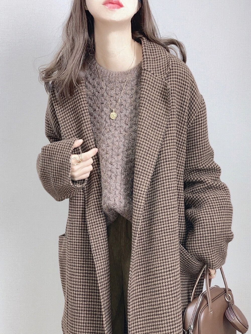 ブラウン系のチェスターコート、ブラウン系のニット/セーター、グリーン系のその他パンツを着用したレディースの冬コーディネートの2枚目の写真