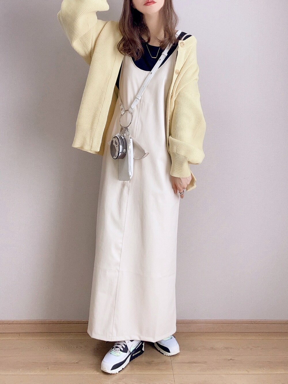 イエロー系のカーディガン/ボレロ、ホワイト系のワンピース、ホワイト系のショルダーバッグを着用したレディースの冬コーディネートの2枚目の写真