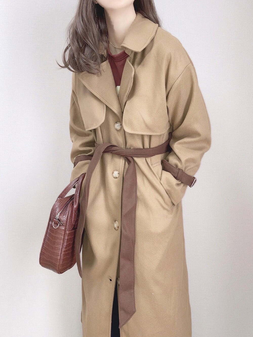 イエロー系のトレンチコート、ブラウン系のスウェット、ブラック系のサロペット/オーバーオールを着用したレディースの秋コーディネートの2枚目の写真