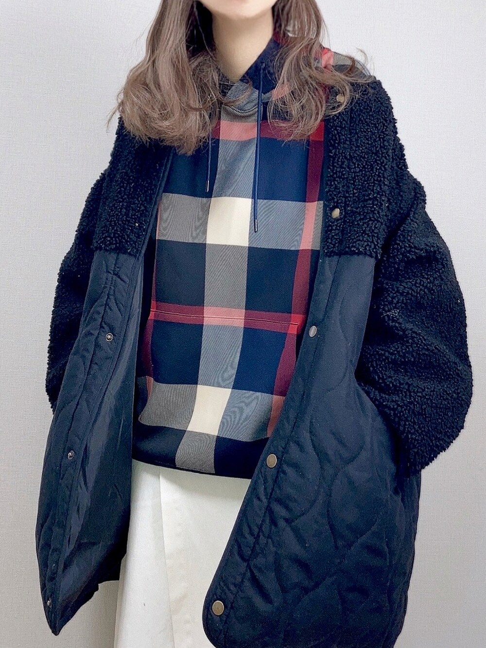 ブルー系のパーカー、ブラック系のブルゾン、ホワイト系のスカートを着用したレディースの冬コーディネートの2枚目の写真