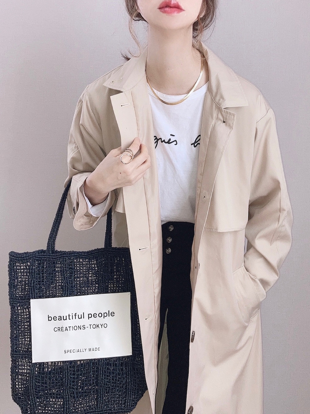 ベージュ系のステンカラーコート、ホワイト系のTシャツ/カットソー、ブラック系のデニムパンツを着用したレディースの冬コーディネートの2枚目の写真