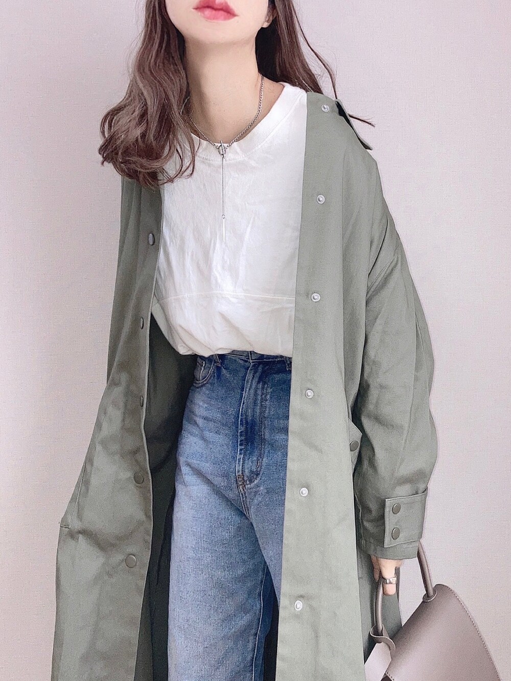 グリーン系のステンカラーコート、ホワイト系のTシャツ/カットソー、ブルー系のデニムパンツを着用したレディースの冬コーディネートの2枚目の写真