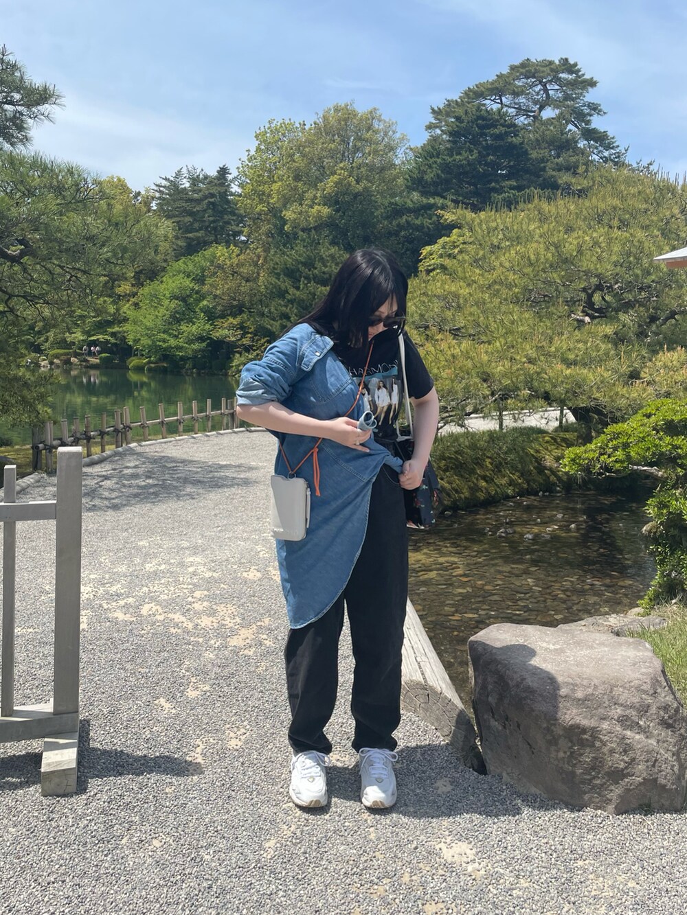 ホワイト系のスニーカー、ブラック系のデニムパンツ、イエロー系のショルダーバッグを着用したレディースの春コーディネートの2枚目の写真