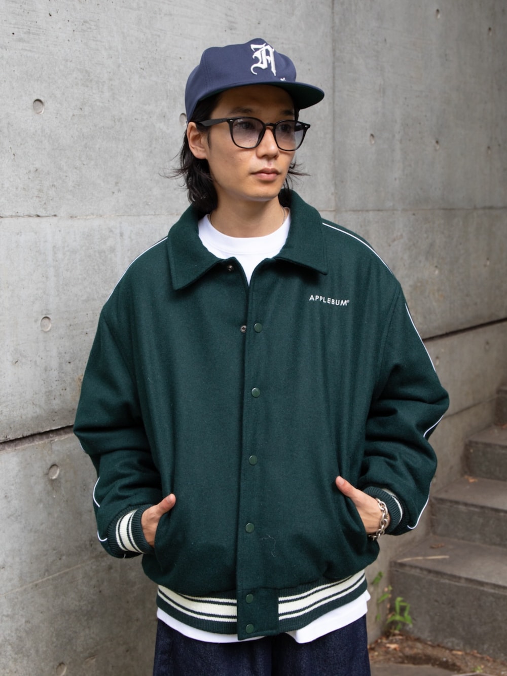 グリーン系のブルゾン、ブルー系のキャップを着用したメンズの秋コーディネートの4枚目の写真