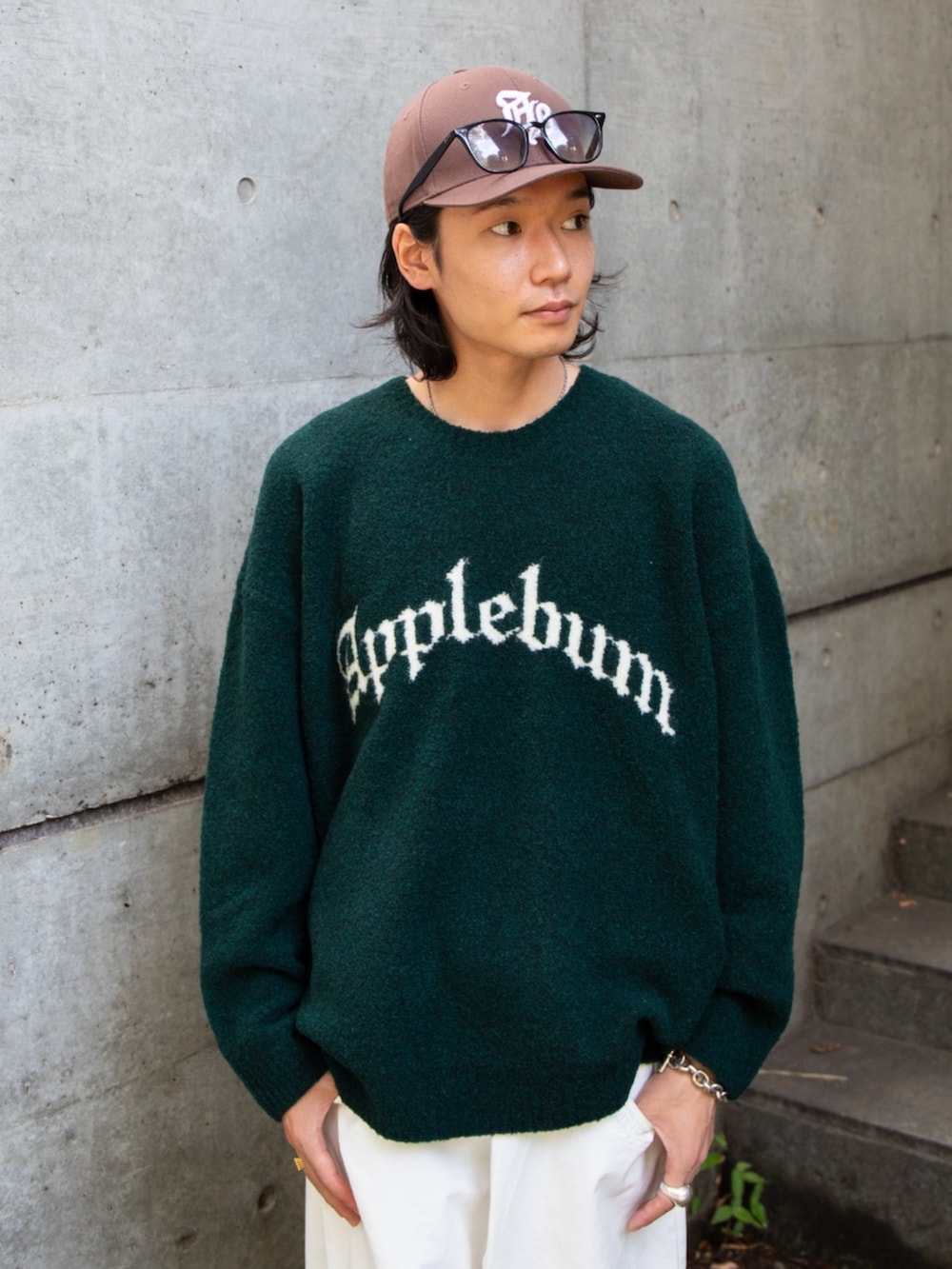 グリーン系のニット/セーター、ブラウン系のキャップを着用したメンズの冬コーディネートの2枚目の写真