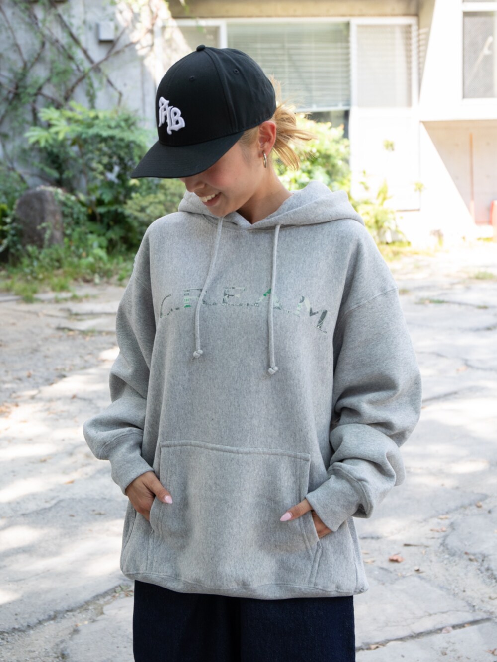 ブルー系のデニムパンツ、グレー系のパーカー、ブラック系のキャップを着用したレディースの秋コーディネートの2枚目の写真