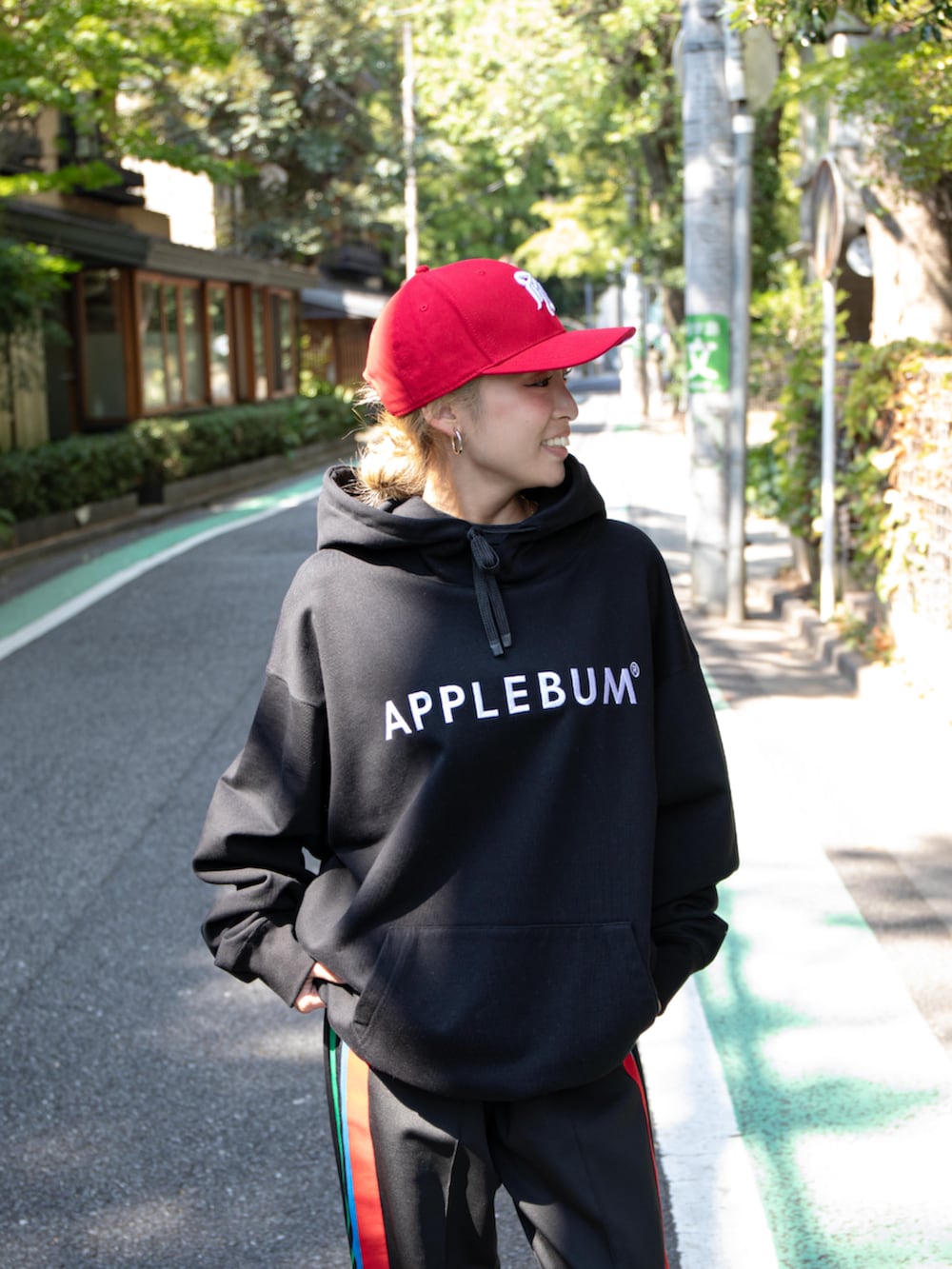 ブラック系のその他パンツ、ブラック系のパーカー、レッド系のキャップを着用したレディースの秋コーディネートの2枚目の写真