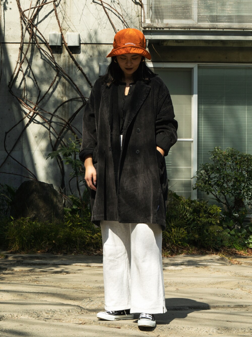 ブラック系のその他アウター、オレンジ系のハットを着用したレディースの春コーディネートの2枚目の写真