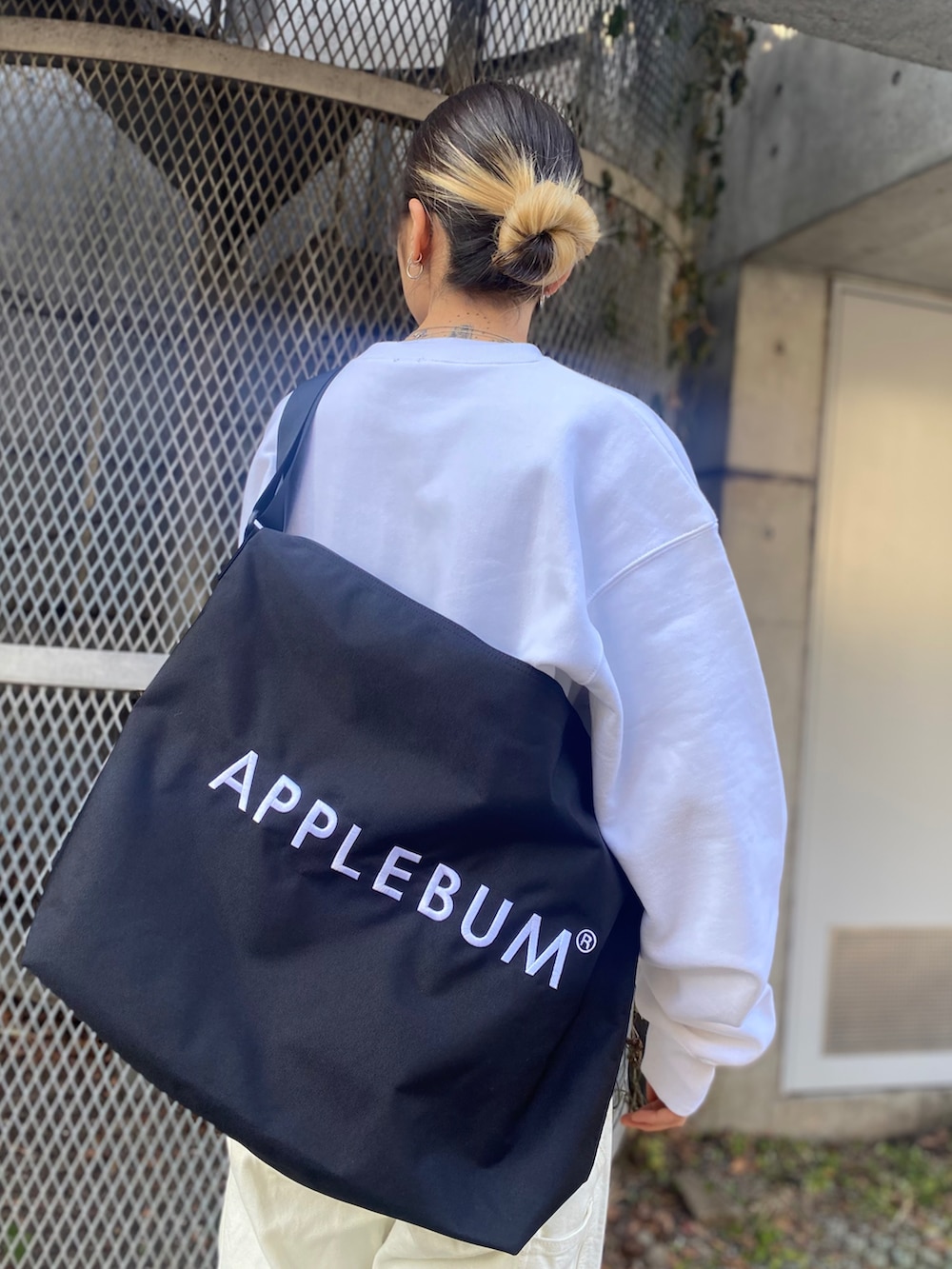 ホワイト系のスウェット、ブラック系のメッセンジャーバッグを着用したレディースの冬コーディネートの3枚目の写真