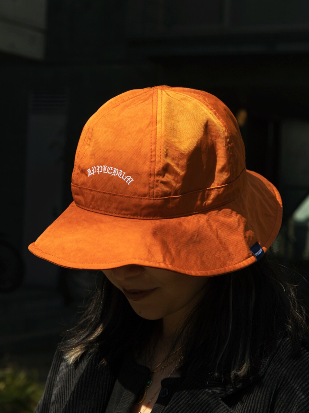 ブラック系のその他アウター、オレンジ系のハットを着用したレディースの春コーディネートの3枚目の写真