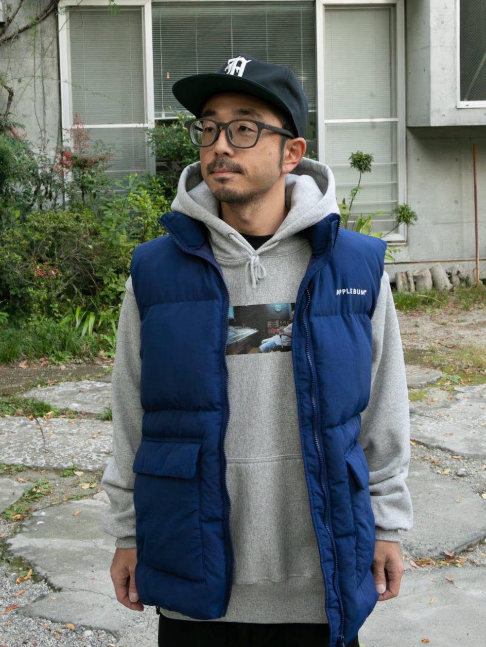 グレー系のパーカー、ブルー系のダウンベスト、ブルー系のキャップを着用したメンズの秋コーディネートの3枚目の写真
