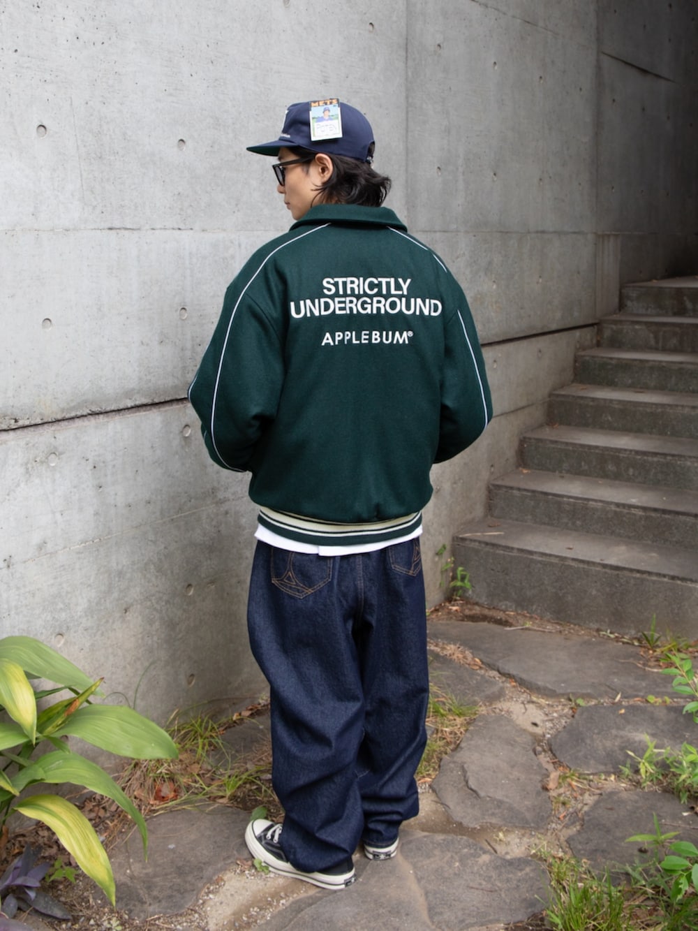 グリーン系のブルゾン、ブルー系のキャップを着用したメンズの秋コーディネートの2枚目の写真