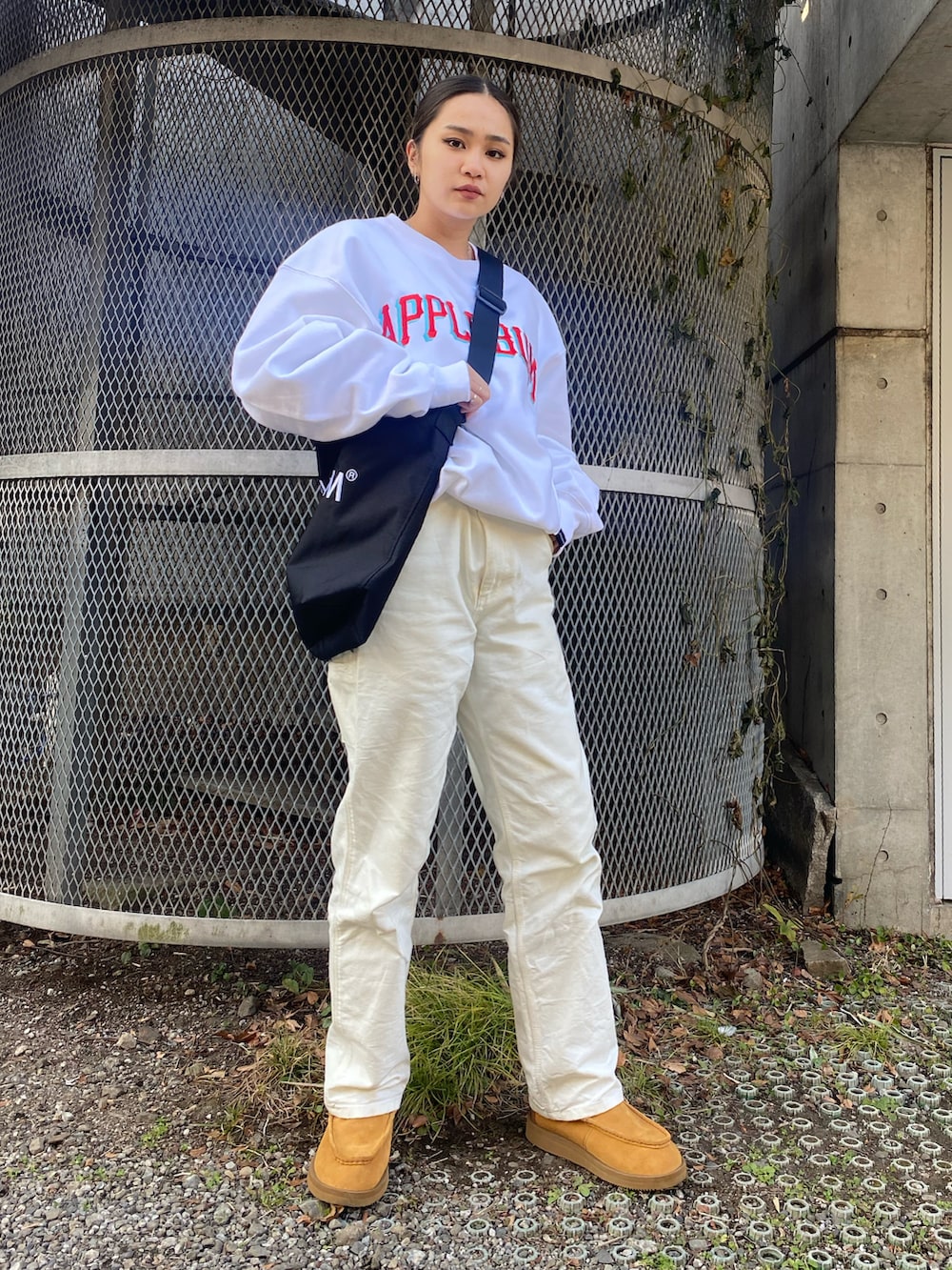 ホワイト系のスウェット、ブラック系のメッセンジャーバッグを着用したレディースの冬コーディネートの2枚目の写真